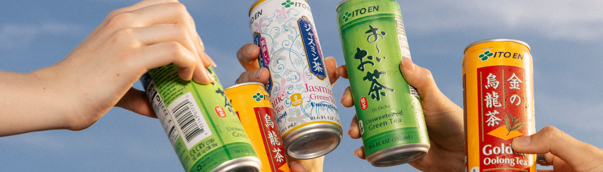 Hands Cheering with cans of Ito Ens Oolong tea, Jasmine green tea, and Oi Ocha green tea